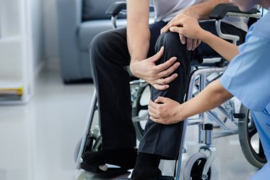 Tekerlekli sandalyede oturan erkek hasta uzman doktorla birlikte tıbbi muayeneye tabi tutuluyor, yaraları tedavi ediliyor uzman doktordan doğru ve düzgün bir tedavi görüyor.