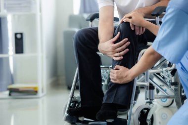 Tekerlekli sandalyede oturan erkek hasta uzman doktorla birlikte tıbbi muayeneye tabi tutuluyor, yaraları tedavi ediliyor uzman doktordan doğru ve düzgün bir tedavi görüyor.