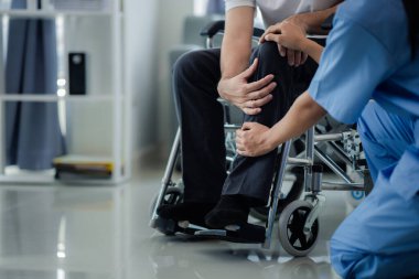 Tekerlekli sandalyede oturan erkek hasta uzman doktorla birlikte tıbbi muayeneye tabi tutuluyor, yaraları tedavi ediliyor uzman doktordan doğru ve düzgün bir tedavi görüyor.
