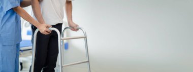 Hasta uzman bir fizyoterapistle fizyoterapi yapıyor, hasta da bir fizyoterapistin yardımıyla yürüyen bir diş teli kullanarak yürüme pratiği yapıyor. Uzmanların fizik tedavi kavramları.