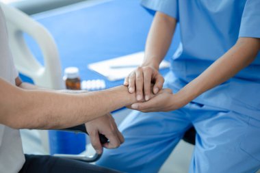 Tekerlekli sandalyede oturan erkek hasta uzman doktorla birlikte tıbbi muayeneye tabi tutuluyor, yaraları tedavi ediliyor uzman doktordan doğru ve düzgün bir tedavi görüyor.