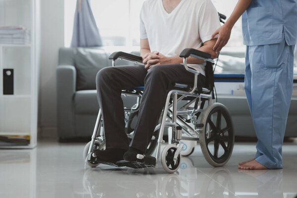 Мужчина, сидящий в инвалидной коляске, проходит медицинское обследование со специалистом-врачом, лечит травмы