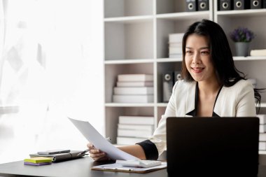 Kurumsal ofiste çalışan genç ve güzel Asyalı bir kadın, iş kadını, şirket kurma işini büyütmek ve modernize etmek için özenle çalışıyor, şirketin pazar ve mali verilerini analiz ediyor..