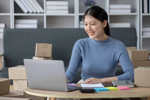 stock image Asian woman online store business owner, online shop owner working from home, posting products for sale on website and accepting orders and packing products for customers with private courier service.