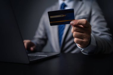 Kredi kartlı takım elbiseli bir adam, kredi kartı sahibi bir işadamı, mağazadaki mal ve hizmetleri ödemek için kredi kartı kullanıyor, internet sitesinden alışveriş yapıyor ve kredi kartıyla ödeme yapıyor. Çevrimiçi alışveriş kavramı.