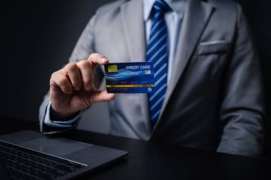 Kredi kartlı takım elbiseli bir adam, kredi kartı sahibi bir işadamı, mağazadaki mal ve hizmetleri ödemek için kredi kartı kullanıyor, internet sitesinden alışveriş yapıyor ve kredi kartıyla ödeme yapıyor. Çevrimiçi alışveriş kavramı.