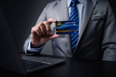 Kredi kartlı takım elbiseli bir adam, kredi kartı sahibi bir işadamı, mağazadaki mal ve hizmetleri ödemek için kredi kartı kullanıyor, internet sitesinden alışveriş yapıyor ve kredi kartıyla ödeme yapıyor. Çevrimiçi alışveriş kavramı.