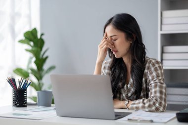 Uzun çalışma saatleri ve iş sorunları yüzünden stres altında olan güzel Asyalı kadın, aşırı çalışma yüzünden ofis sendromu geçiren genç iş kadını, ağrıya ve baş ağrısına neden oluyor. Ofis sendromu kavramı.