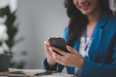 Telefondaki verilere bakan güzel Asyalı kadın, ofiste çalışan iş kadını, şirket kurma işini büyütmek ve modernize etmek için, şirketin pazar ve mali verilerini analiz ediyor..