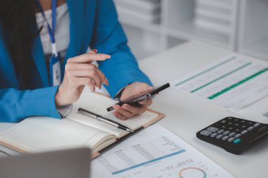 Telefondaki verilere bakan güzel Asyalı kadın, ofiste çalışan iş kadını, şirket kurma işini büyütmek ve modernize etmek için, şirketin pazar ve mali verilerini analiz ediyor..