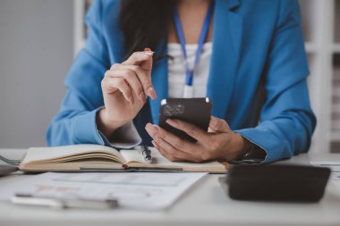 Telefondaki verilere bakan güzel Asyalı kadın, ofiste çalışan iş kadını, şirket kurma işini büyütmek ve modernize etmek için, şirketin pazar ve mali verilerini analiz ediyor..