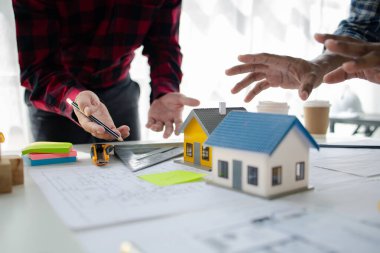 The home design architects are reviewing the house plan draft, the project commissioned by the client, and the custom design before delivery. Interior design and decoration ideas.