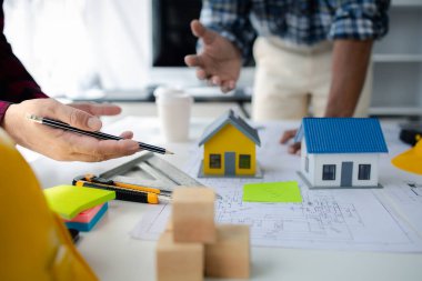 The home design architects are reviewing the house plan draft, the project commissioned by the client, and the custom design before delivery. Interior design and decoration ideas.