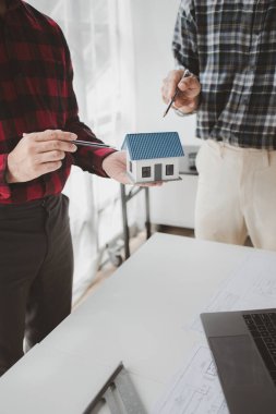 The home design architects are reviewing the house plan draft, the project commissioned by the client, and the custom design before delivery. Interior design and decoration ideas.