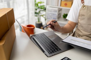 Çalışan, internetteki internet sitelerinden sipariş veren müşterilerin siparişlerini onaylayan ve teslimat için paketleyen bir adam. Çevrimiçi ürün satma kavramı.