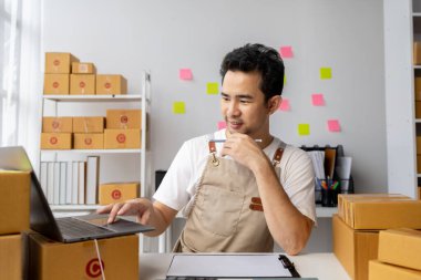 Erkek çevrimiçi dükkan sahibi, çevrimiçi dükkan sahibi ürünleri web sitesinde dağıtıyor, ürünleri siparişlere göre paketliyor ve özel nakliye şirketi tarafından dağıtılıyor. İnternetten alışveriş konsepti. Ticaret mi?.