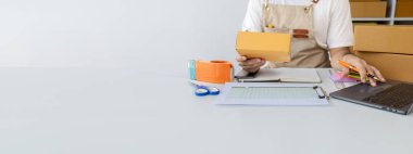 Bir kişi not defterine satış verileri yazıyor, çevrimiçi ürünler satıyor, online alışveriş sitelerinden sipariş veren müşterilerin siparişlerini paketliyor. Ürün çevrimiçi ve e-ticaret kavramı.