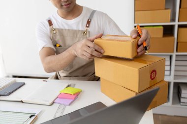 Paket kutusuna müşterinin adresini yazan, internetten ürün satan, online alışveriş sitelerinden sipariş veren müşterilerin siparişlerini paketleyen biri. Ürün çevrimiçi ve e-ticaret kavramı.
