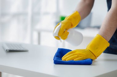 Odayı temizleyen kişi, temizlik personeli şirket odasındaki masaları silmek için dezenfektan ve bez kullanıyor. Temizlik personeli. Organizasyondaki temizliği sürdürmek.