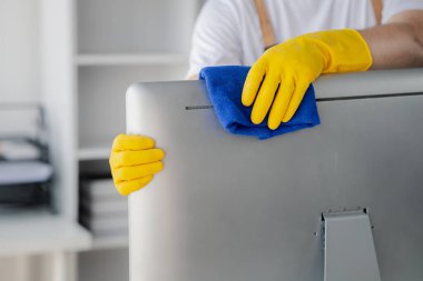 Temizlik odası, temizlik işçisi şirket ofisindeki bilgisayar ekranını silmek için bez kullanıyor. Temizlik personeli. Örgütteki temizlik kavramı.