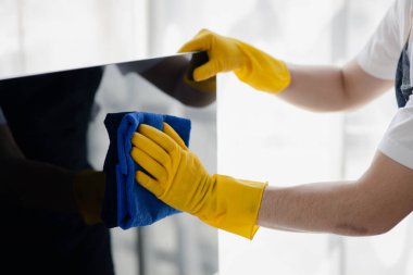 Temizlik odası, temizlik işçisi şirket ofisindeki bilgisayar ekranını silmek için bez kullanıyor. Temizlik personeli. Örgütteki temizlik kavramı.