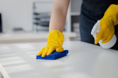 Odayı temizleyen kişi, temizlik personeli şirket ofisindeki masayı silmek için bez ve dezenfektan kullanıyor. Temizlik personeli. Organizasyondaki temizliği sürdürmek.
