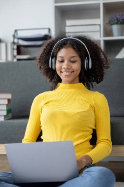 Amerikalı kadın hafta sonları oturma odasında oturuyor, kulaklık takıyor, müzik dinliyor ve günlerini sosyal medyada film izleyerek ve müzik dinleyerek geçiriyor. Tatil aktiviteleri konsepti.