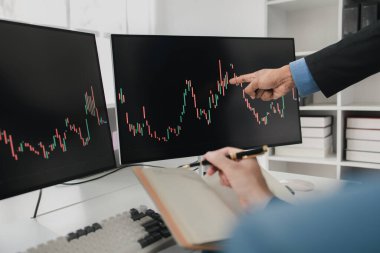 Borsa grafik ekranı olan iki yatırımcı, hisse senedi dalgalanması analizi, kar için hisse senedi alım satımı, borsa dalgalanması grafik ekranı, kar ticaret analizi.