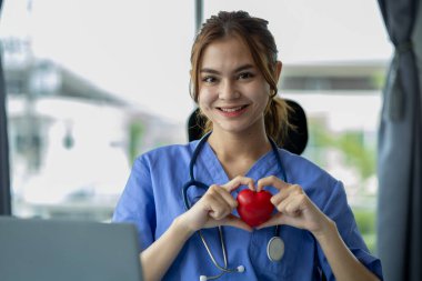 Tıbbi giysiler içinde genç ve güzel bir bayan doktor bir hastane ofisinde oturur ve çalışır, profesyonel bir doktor ve bir hastaya danışır, bir hastalığı detaylı bir şekilde tedavi eder. Kadın doktor konsepti.