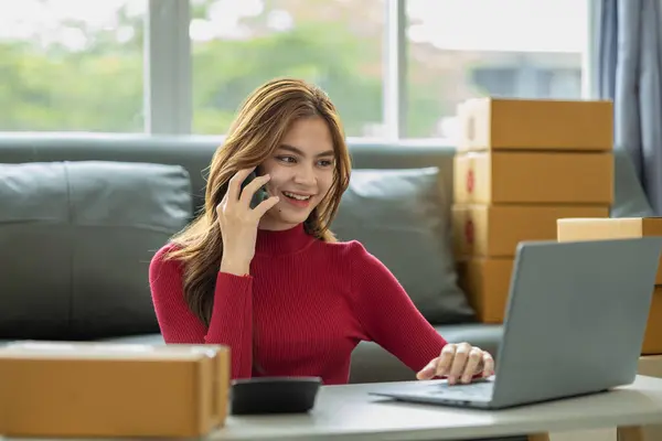Online sales business owner talks on phone with customers, she sells products on the website and manages the online store on the internet, taking orders and packing products for delivery to customers.