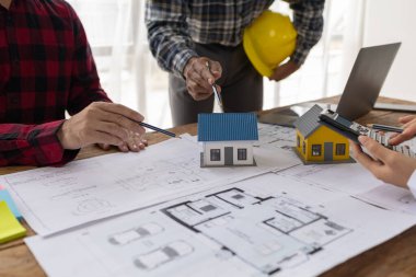 İç mimarlar, mühendisler ve mimarlar tasarım ilkeleri ve planlarına göre evin inşasını planlamak için birlikte çalışırlar, gözden geçirme ve düzeltmeler yapma planlarına bakarlar..