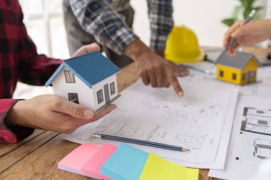 İç mimarlar, mühendisler ve mimarlar tasarım ilkeleri ve planlarına göre evin inşasını planlamak için birlikte çalışırlar, gözden geçirme ve düzeltmeler yapma planlarına bakarlar..