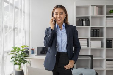 Asyalı kadın şirket ofisinde telefonla konuşuyor, iş kadını üst düzey yönetici şirket yöneticisi ofiste telefonla konuşuyor, iş görüşmeleri. İş yönetimi kavramı.