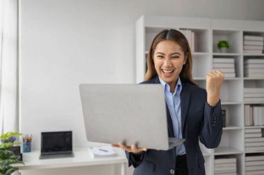 Şirketin kârlı satışlarına ve kazanç özetine bakan Asyalı kadın, mutlu bir ifade sergiliyor, şirketin hedefine ulaşmasından ve daha fazla büyümesinden memnun..