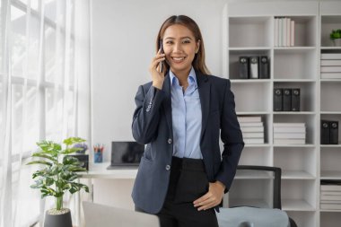 Asyalı kadın şirket ofisinde telefonla konuşuyor, iş kadını üst düzey yönetici şirket yöneticisi ofiste telefonla konuşuyor, iş görüşmeleri. İş yönetimi kavramı.