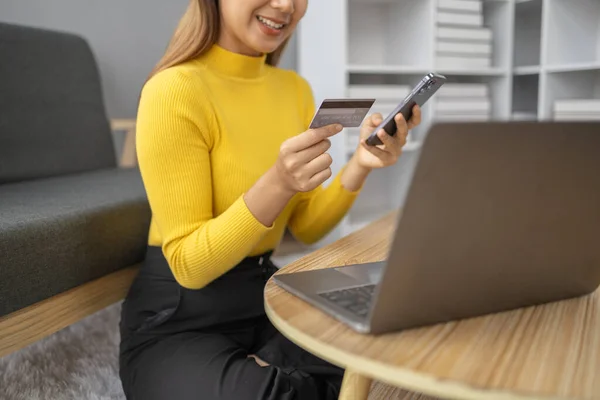 stock image Asian woman resting in living room, businesswoman spending her holiday shopping online on website, she shop on website and pay by credit card. The concept of using a credit card to pay online.