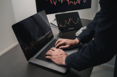 Dizüstü bilgisayarın klavyesinde yazan kişi, hisse senedi yatırımcısı, hisse senedi alım-satımı, karlı ticaret için borsa analizi, kripto para yatırımı. Hisselere yatırım yapma kavramı.