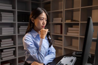 Asyalı kadın gecenin bir yarısı ofiste fazla mesai yapıyor, çalışanlar işi zamanında bitirmek için fazla mesai yapıyor. Şirket çalışanlarının fazla mesai ve sıkı çalışma kavramı..