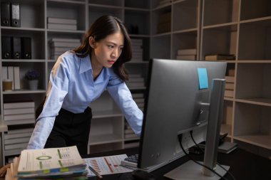 Asyalı kadın gecenin bir yarısı ofiste fazla mesai yapıyor, çalışanlar işi zamanında bitirmek için fazla mesai yapıyor. Şirket çalışanlarının fazla mesai ve sıkı çalışma kavramı..