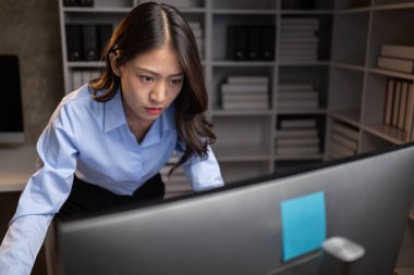 Asyalı kadın gecenin bir yarısı ofiste fazla mesai yapıyor, çalışanlar işi zamanında bitirmek için fazla mesai yapıyor. Şirket çalışanlarının fazla mesai ve sıkı çalışma kavramı..