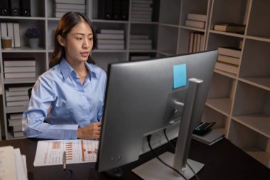 Asyalı kadın gecenin bir yarısı ofiste fazla mesai yapıyor, çalışanlar işi zamanında bitirmek için fazla mesai yapıyor. Şirket çalışanlarının fazla mesai ve sıkı çalışma kavramı..