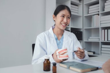 Kadın diş hekimi, hastanın dişlerini kontrol ediyor, dişçi, hastanın semptomları ve endodontik tedavi yönergeleri hakkında tavsiye veriyor. Diş tedavisi kavramı.