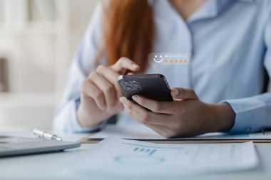 Akıllı telefonu olan Asyalı bir kadın, mağaza değerlendirmelerini ve online alışveriş siparişlerini değerlendiriyor. Mağazalara yıldız vermek, servisi kullanma kararları için yapılan bir değerlendirmedir. Hizmet derecesi kavramı.