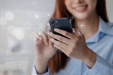 Asyalı kadının elinde akıllı telefon var. Sipariş vermeden önce internetten akıllı telefondan alışveriş yapıyor ve sosyal medyada ürünleri gözden geçiriyor. İnternetteki mal ve hizmetleri ödemek için kredi kartı kullanmak.