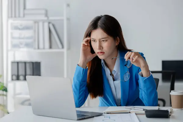 Asian woman in a startup company office, businesswoman poses stressed and body aches due to long hours of hard work, office syndrome among working people. Office syndrome concept and hard work.