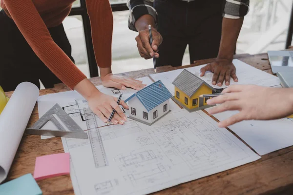 Group architects and engineers build houses and conference buildings together to design and build structures, sketch house plans to meet construction standards. Ideas for designing and building house.