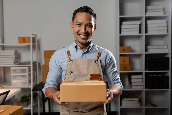 Asian business owners sell products on websites and online platforms. Business owners sell their products online and pack the products into parcels to deliver to customers via courier service.