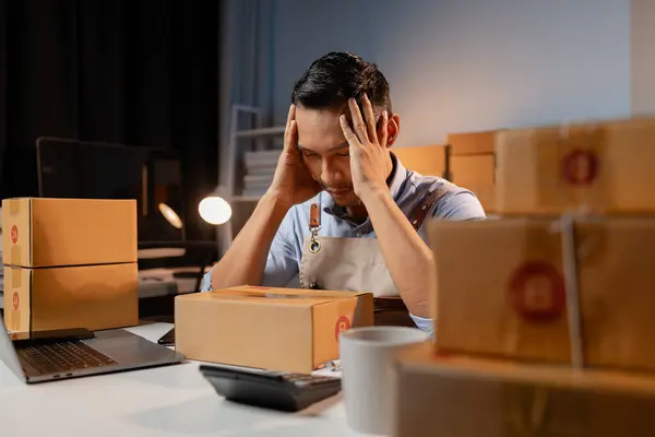 Owner of business selling products on websites and online platforms, feeling stressed due to decreased sales causing business losses, packs products into parcel boxes for delivery with courier service