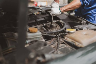 Tamirci, merkezden tamir için gelen bir arabanın motorunu inceliyor. Profesyonel motor uzmanı, araba tamiri, araba arızası. Araba bakım ve onarım konsepti.