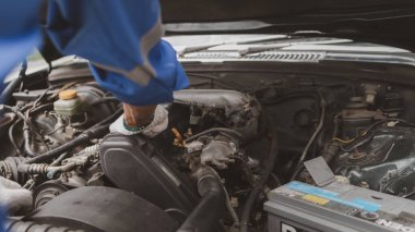Tamirci, merkezden tamir için gelen bir arabanın motorunu inceliyor. Profesyonel motor uzmanı, araba tamiri, araba arızası. Araba bakım ve onarım konsepti.